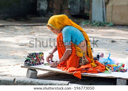 KOCHI, INDIA - FEBRUARY 25: Indian woman in colorful sari sells souvenirs, bangles and cheap jewelry at street market place on Febr 25, 2013. Fort Cochin (Kochin),  Kerala, India