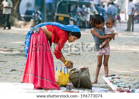 KOCHI, INDIA - FEBR 25: Unidentified Indian woman in sari and her children sells souvenirs, bangles and cheap jewelry at street market place on Febr 25, 2013. Fort Cochin (Kochin),  Kerala, India