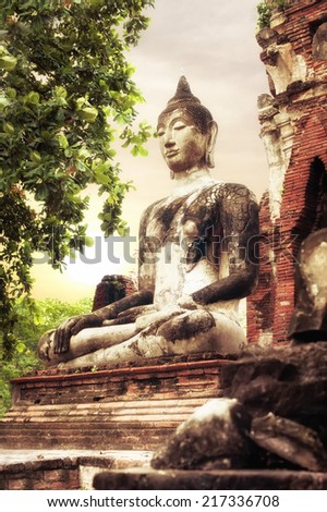Asian religious architecture. Ancient sandstone sculpture of Buddha at Wat Mahathat ruins under sunset sky. Ayutthaya, Thailand travel landscape and destinations