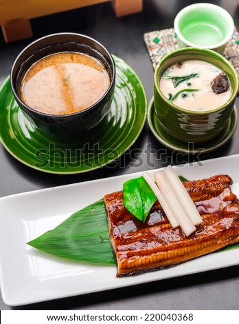 Premium quality grilled eel, miso soup and sake served in Japanese restaurant. Asian food background