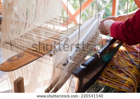 Woman weaving silk in traditional way at manual loom. Laos