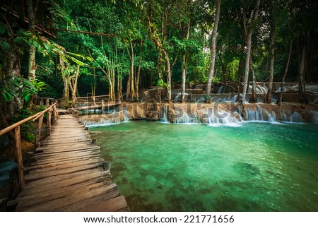 Jangle landscape tropical rain forest landscape with wooden bridge with amazing turquoise water of Kuang Si cascade waterfall at tropical rain forest near Luang Prabang, Laos