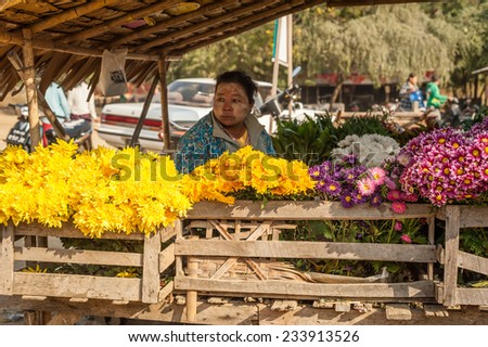 BAGAN, MYANMAR - JANUARY 16, 2014: Burmese woman selling flowers at traditional asian marketplace. Burma travel destinations