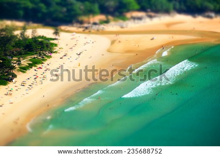 Tropical sandy beach landscape from high view point tilt shift effect. Beautiful turquoise ocean and people relaxing in waives. Rawai, Ya Nui beach, Phuket, Thailand