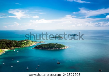 Tropical ocean landscape with Koh Kaeo island at turquoise ocean waives with boats near Ya Nui beach. Rawai, Phuket, Thailand
