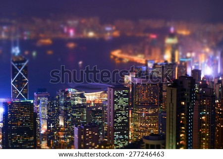 Night aerial view panorama of Hong Kong skyline and Victoria Harbor. Tilt shift effect. Abstract futuristic cityscape with modern skyscrapers