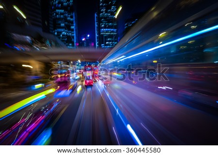 Abstract cityscape traffic background with red tram under the bridge. Motion blur, art toning. Moving through modern city street with illuminated skyscrapers. Hong Kong