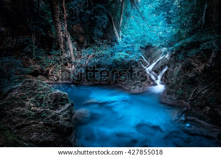 Mystery night at deep tropical rain forest with flowing cascade waterfall. Fantasy jungle landscape.  Erawan, National Park Kanchanaburi, Thailand