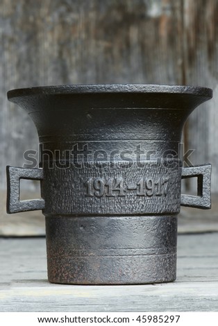 Ancient kitchen and medical utensil. Old metal mortar on wooden background, aged 1914-1917