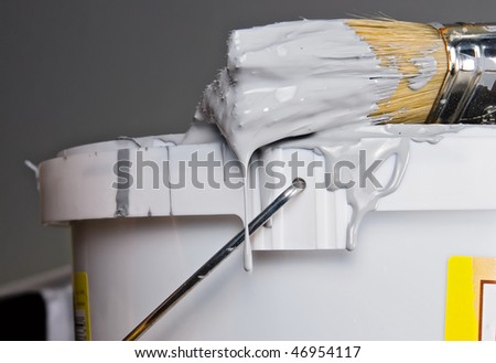 Paint bucket and paintbrush over gray wall