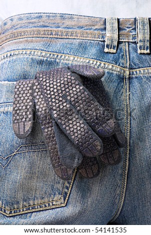 Industrial tools and instruments. Working glove in the back pocket of old used jeans