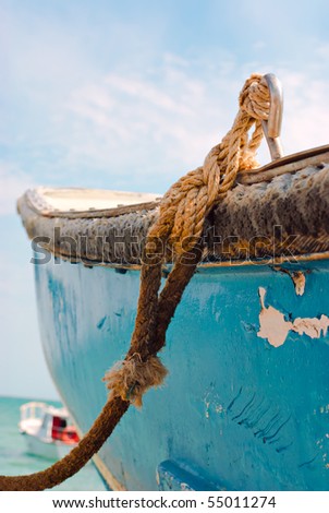 Boat on sea. Old blue painted fishing boat tied with rope at seacoast