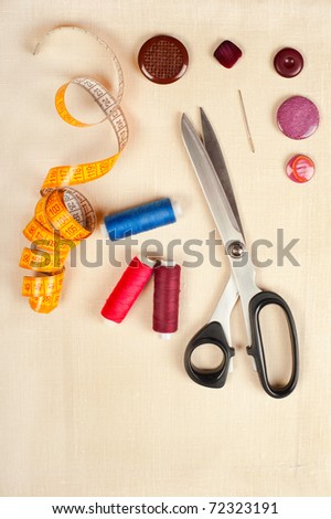 Tailor tools for craft. Set from measuring tape, buttons, bobbins of thread, needle and scissors on linen
