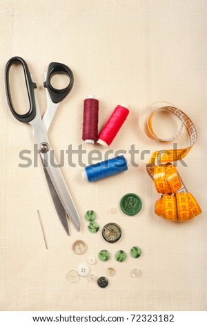 Tailor tools for craft. Set from measuring tape, buttons, bobbins of thread, needle and scissors on linen canvas