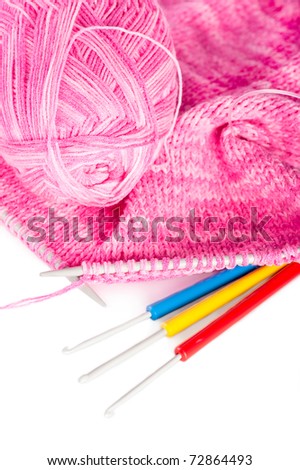Knit woolen texture. Pink fabric with needles, yarn ball and and knitting hooks