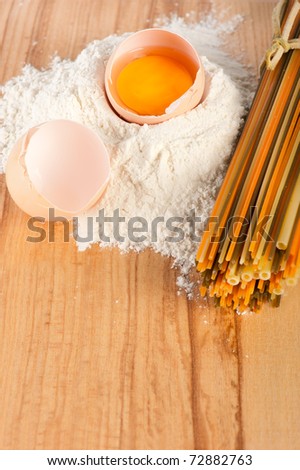 Bakery ingredient. Flour with eggs and pasta on wooden background