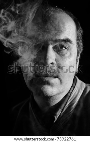 Black&White studio portrait of a mustached man in cigarette smoke over black