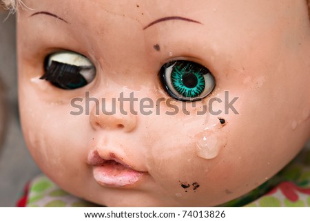 Broken doll crying. Concept Abandoned Person. Close up of an old doll`s face with tear