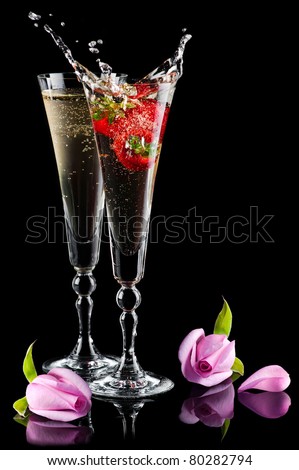 Two glasses of sparkling splashing wine (champagne) with pink roses and strawberry on black