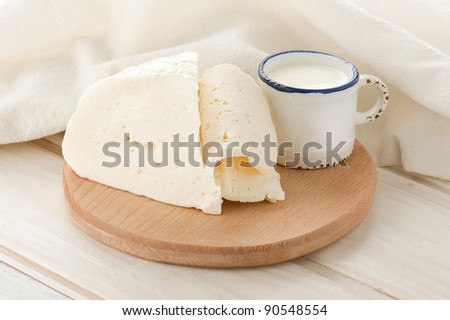 Breakfast with milk and soft sheep cheese on old wooden table with linen tablecloth