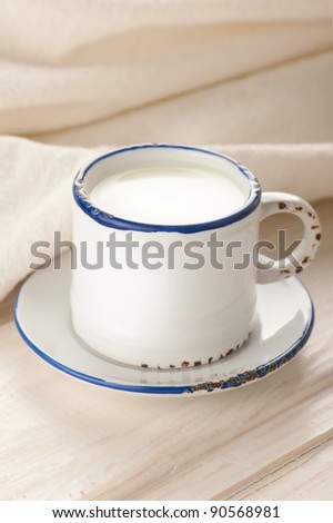 Breakfast with milk. Milk in vintage cup on old wooden table with linen tablecloth