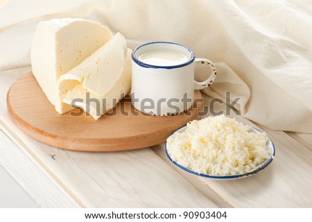 Breakfast with milk, cottage and soft sheep cheese on old wooden table with linen tablecloth