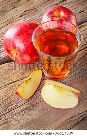 Apple juice. Fresh ripe apples and glass of juice on old wooden table background