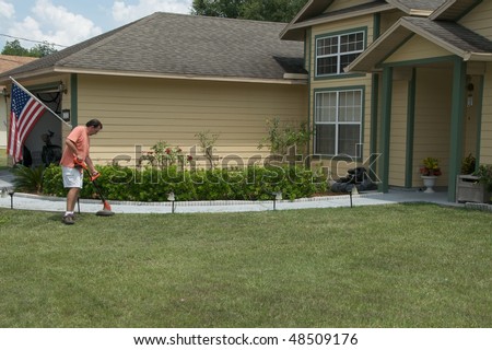 Caucasian male edging the sidewalk in front of a single family residence.