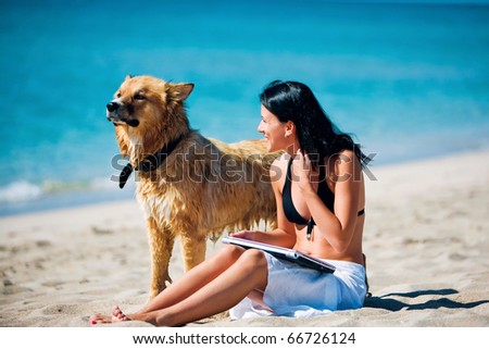 Beautiful young woman and dog on the beach