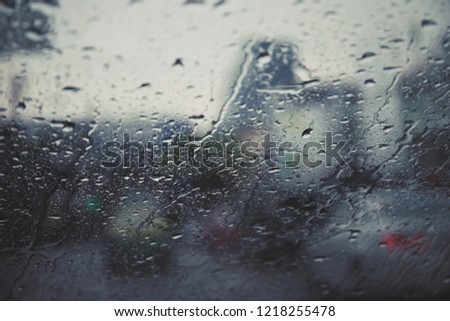 Drops Of Rain Drizzle on the glass windshield in the evening. street in the heavy rain. Bokeh Tail light. soft Focus. Please drive carefully, slippery road. soft focus.