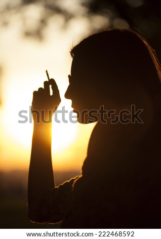 Young Girl Smoking In Park At Sunset