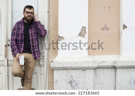 Man With Beard And Glasses Holding To Go Cup And Talking On Mobile Smart Phone