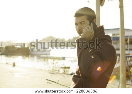Handsome Muscle Man Talking on Mobile Smart Phone Outdoors At River Bank