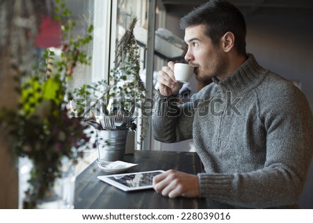Handsome Man Drinking Coffee And Using Tablet Computer Inside Cafe Bar