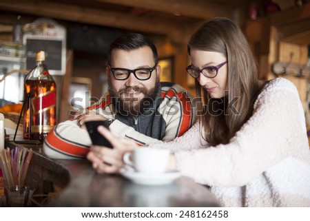 Friends in a cafe using phone indoor