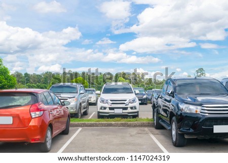 Car parked in asphalt parking lot and one empty space parking  in nature with trees, beautiful cloudy sky background .Outdoor parking lot with fresh ozone and green environment concept