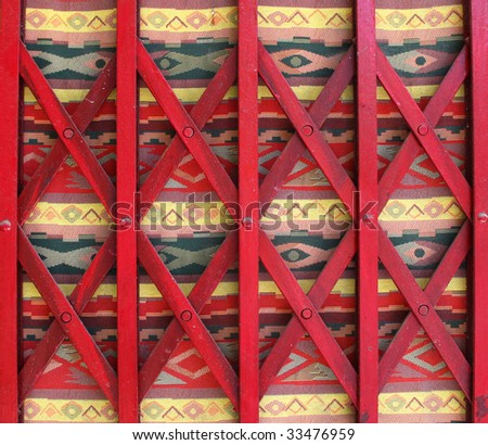Closed store folding gate with colorful tapestry hanging behind it