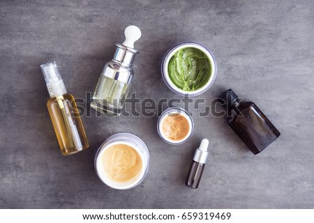 Bottles and jars with natural skincare cosmetics, creams and oils on dark background. Plant-based beauty products. Top view