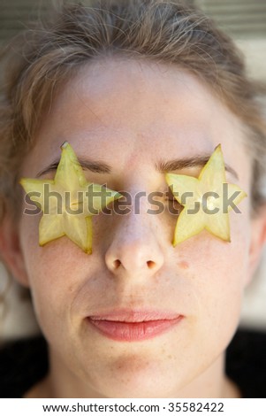 carambola fruit as star on the eyes of a young smiling woman