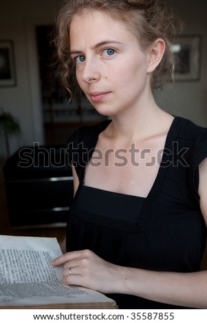 portrait of a young woman reading a book as a student, before modern minimalistic interior design of a library (natural beauty)