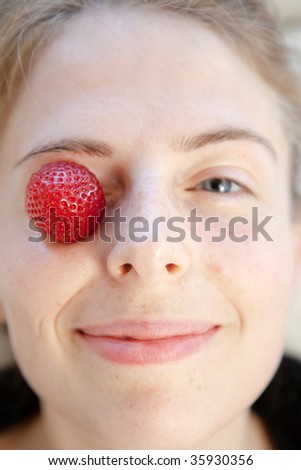 strawberry on the eyes of a young nordic style smiling woman (natural beauty)