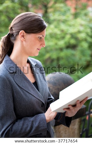 young woman reading a book, outside