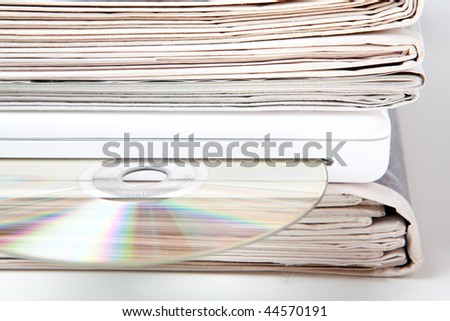 stack of newspapers and laptop computer with CD