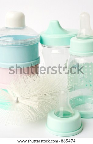 Bottles, nipples, bottle brush and container on white