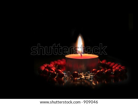 Red Candle and rosary against black (focus on the candle)