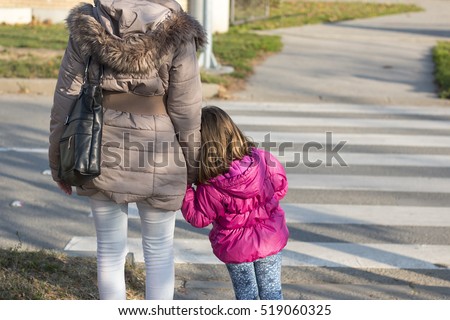 Mother with little daughter waiting to crosswalk street. Zebra crossing
