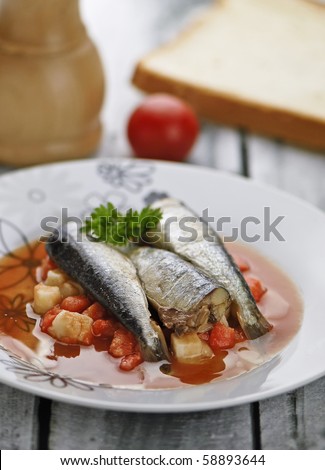 Served sardines with vegetables sauce, parsley tomatoe, on a wooden table
