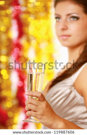Beautiful young brunette woman drinking champagne at christmas party. Isolated on decorated background