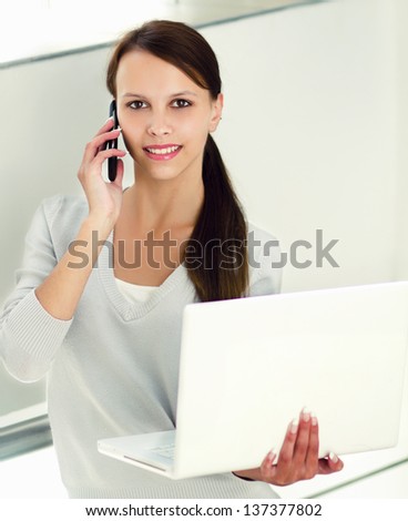 Young woman sitting with laptop and talking on the phone,Isolated on white background