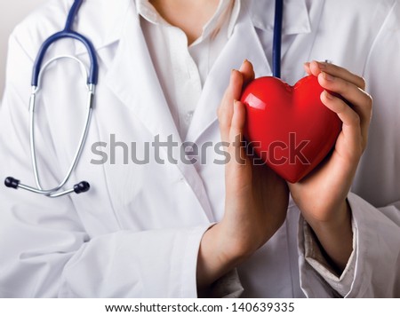 Female doctor with stethoscope holding heart, isolated on white background